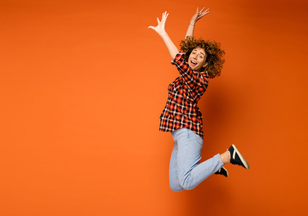 A woman jumping in the air and smiling.