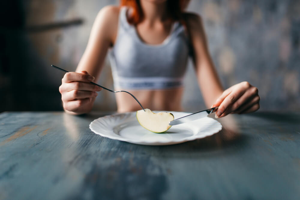 Une femme anorexique qui mange un morceau de pomme. 