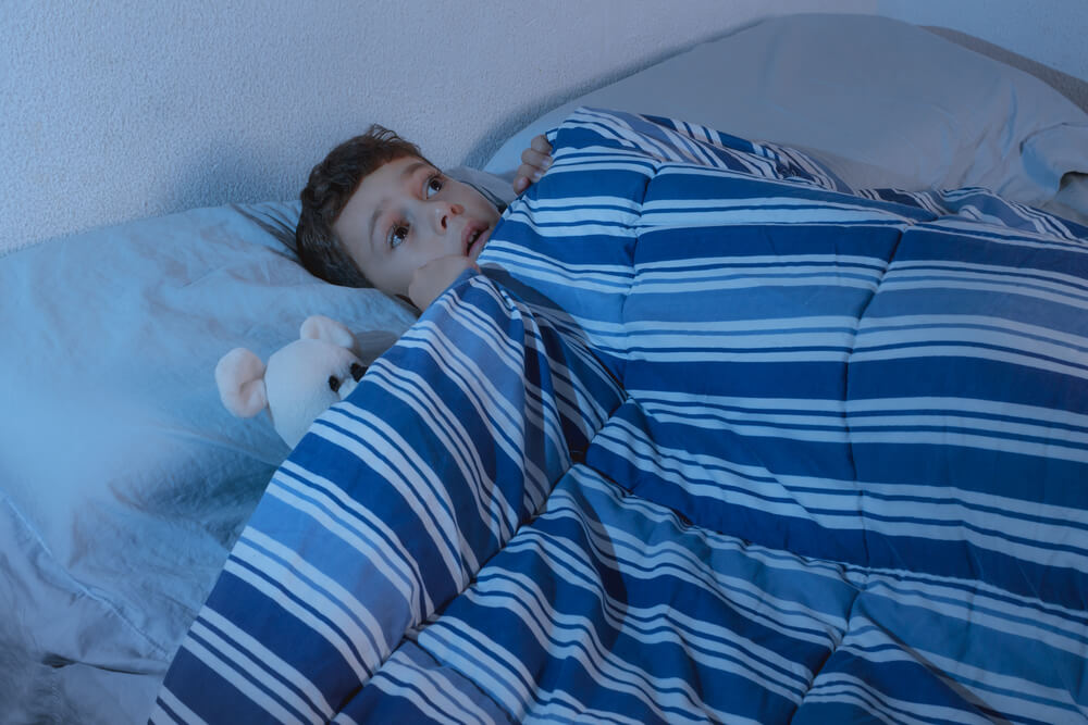 Un enfant qui a peur dans son lit;