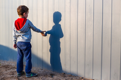 Un enfant qui regarde le reflet de son ombre sur un mur.