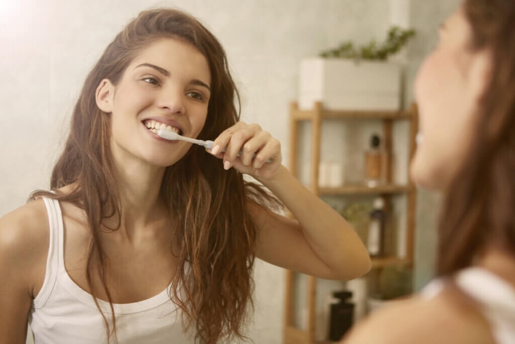 Mujer cepilla sus dientes por mal aliento.