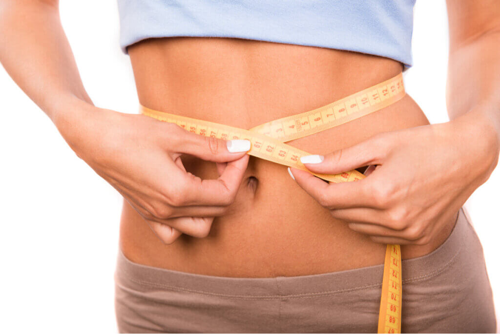 A woman measuring her waistline.