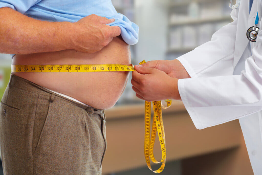 Médico mide circunferencia abdominal.