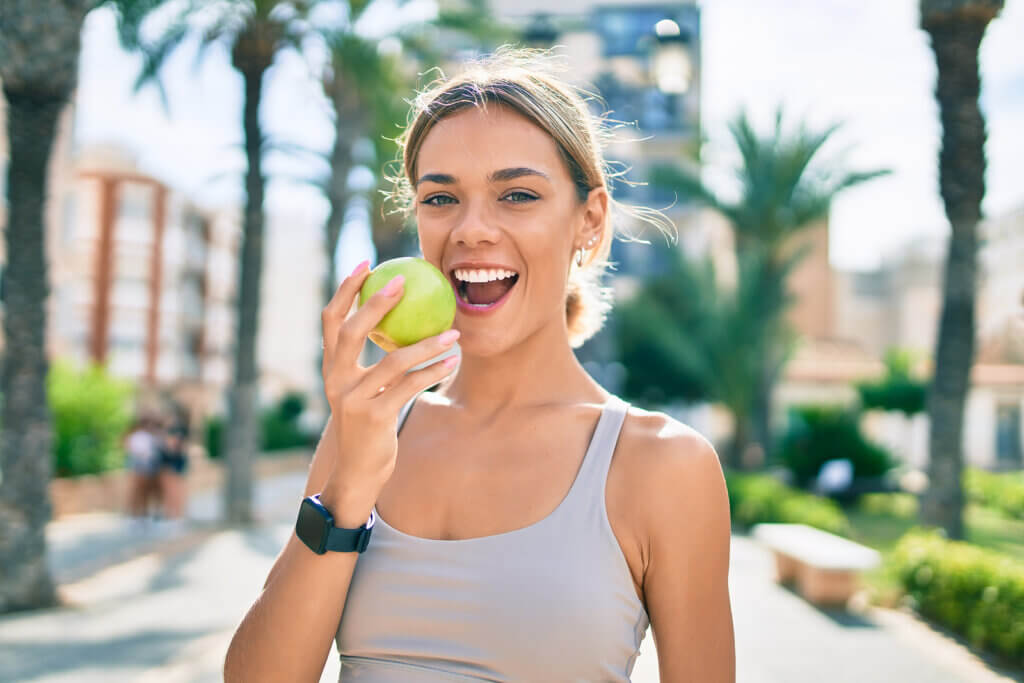 Mujer come fruta para hacer ejercicio físico.