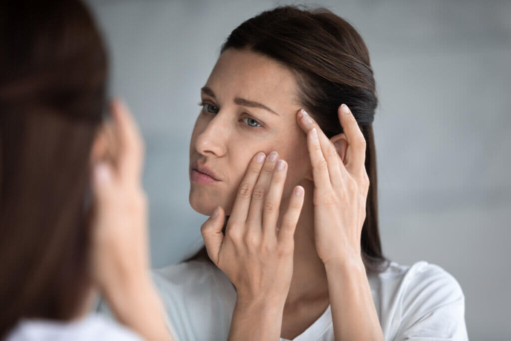 La donna controlla il viso per mancanza di collagene.