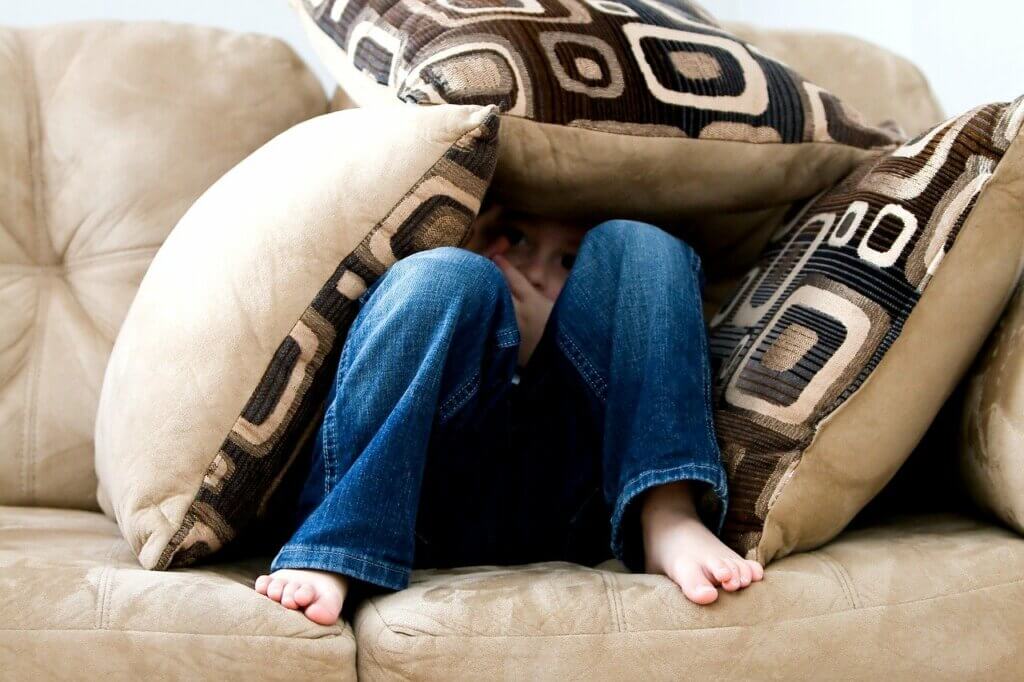 A child hiding under couch cushions.