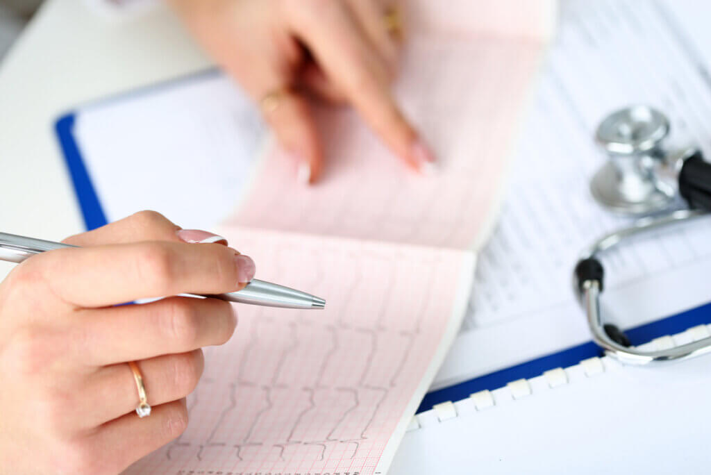 Médico lee un electrocardiograma de una persona que tiene beneficios por bailar.