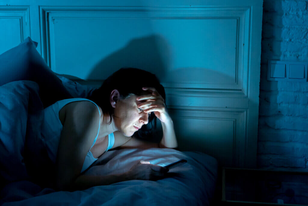 Insomnio en mujer que usa celular de noche.