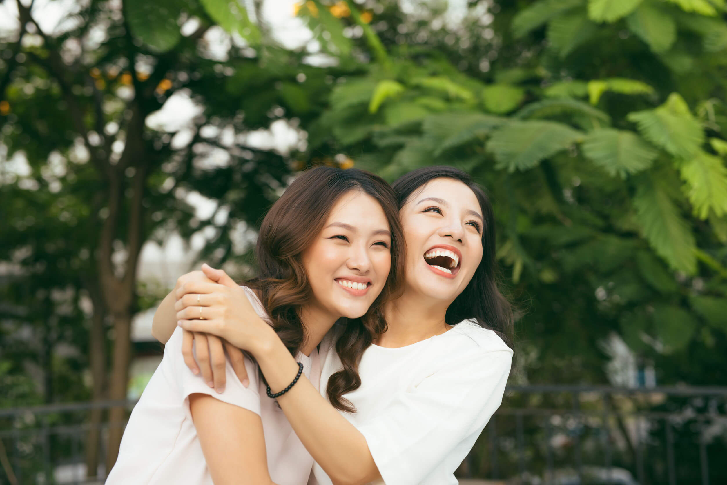 Two Asian women laughing and embracing.