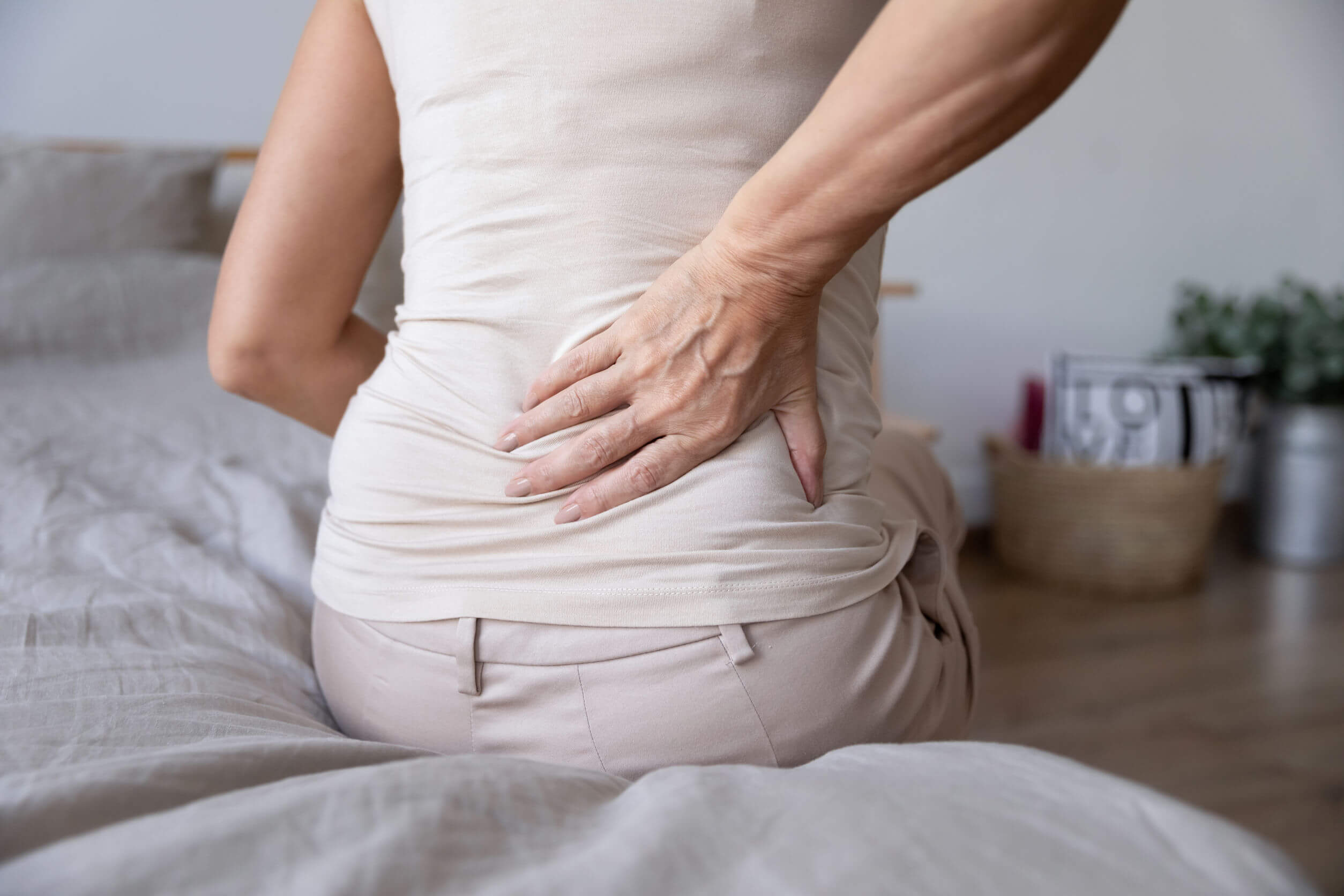 A woman getting out of bed with lower back pain.