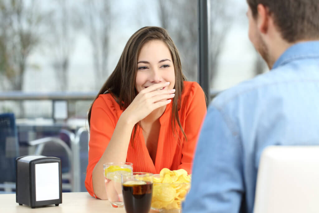 Mujer con halitosis tiene pena en una cita.