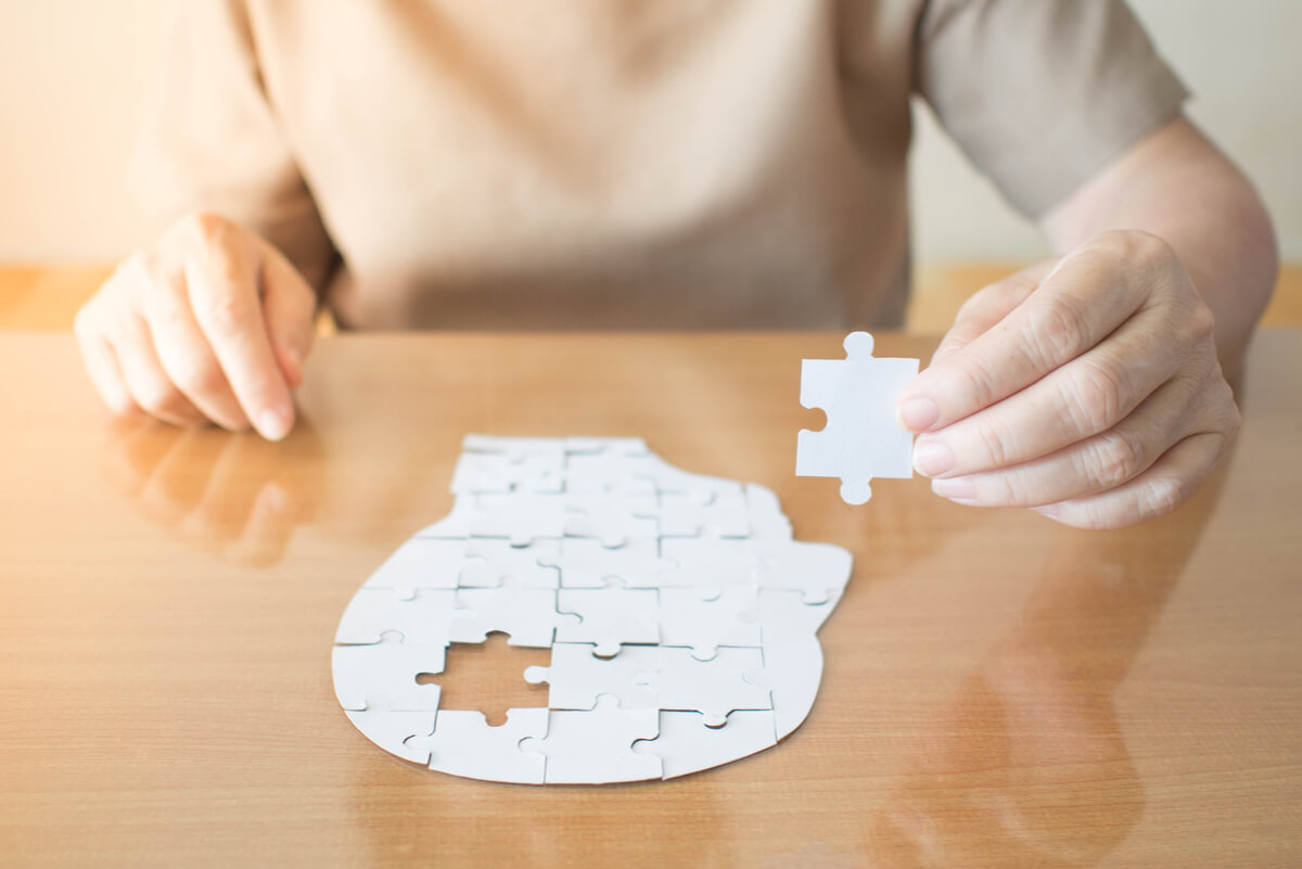 A woman putting together a puzzle in the shape of a head turned sideways.