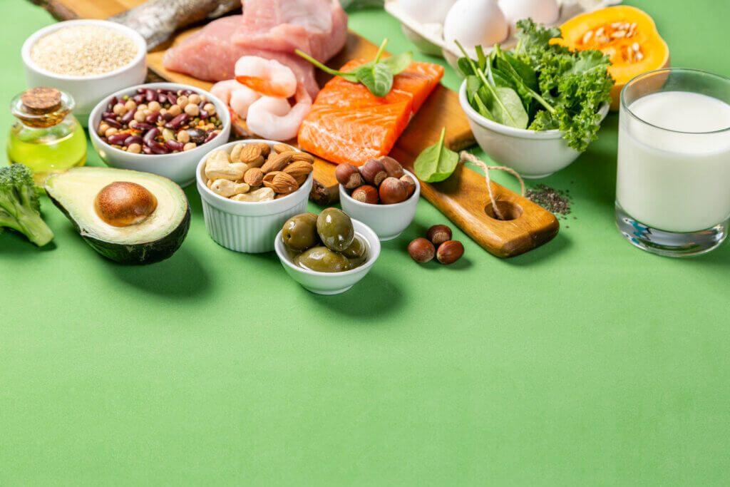 Foods that are included in the Mediterranean diet, including olive oil, olive, nuts, legumes, seeds, vegetables, avocado, chicken, shrimp, salmon and milk. 