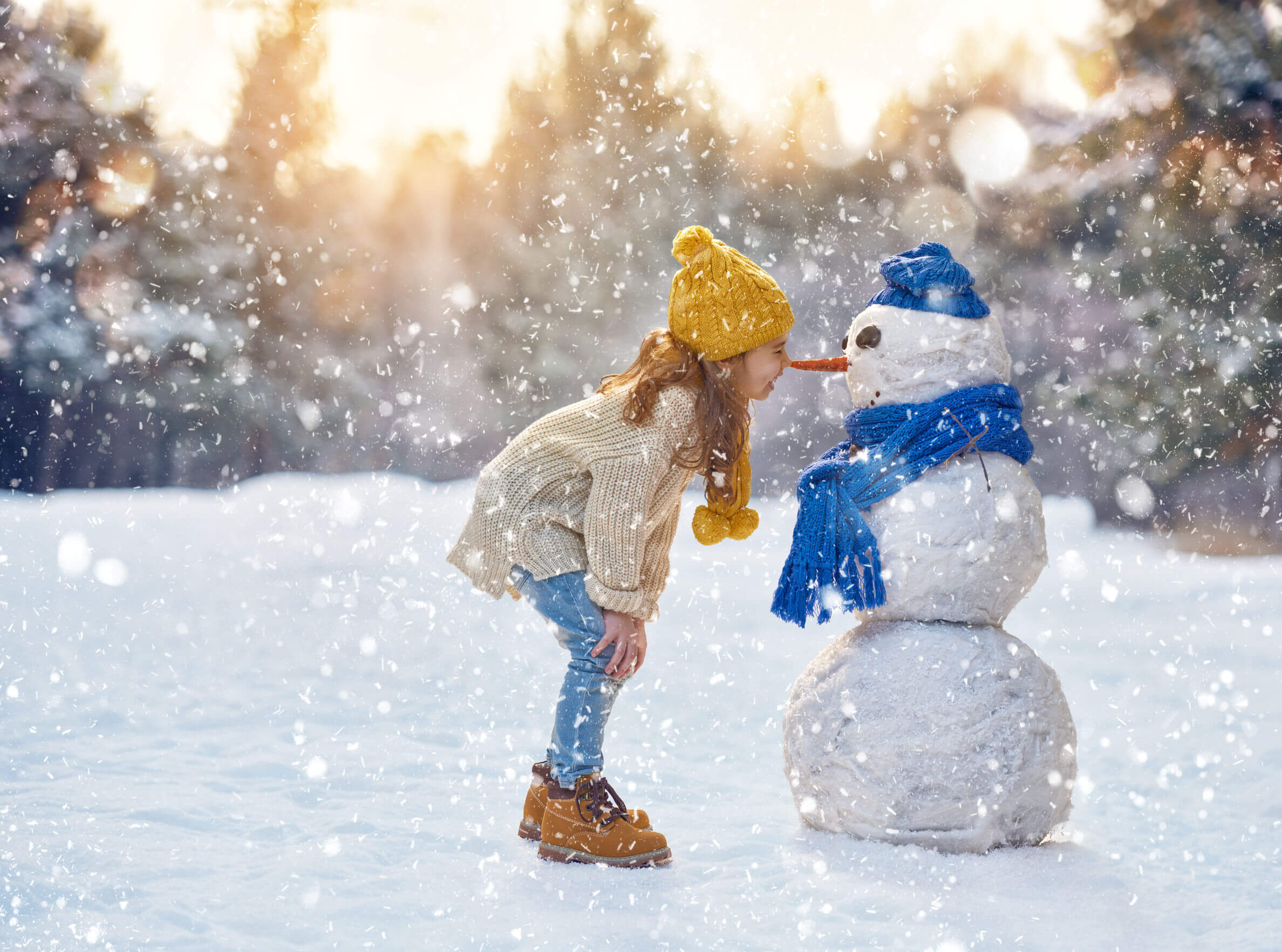 Une petite fille à côté d'un bonhomme de neige. 