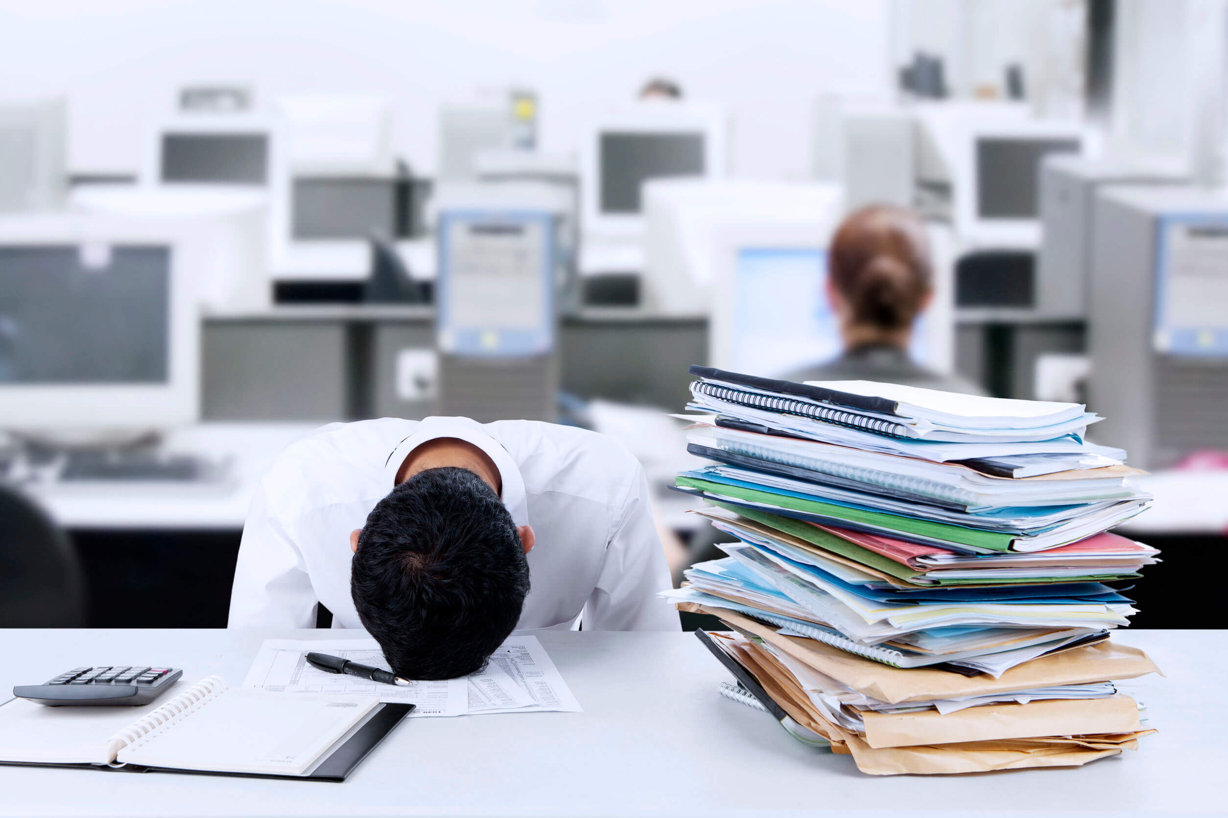 Un homme fatigué au travail, la tête sur son bureau.