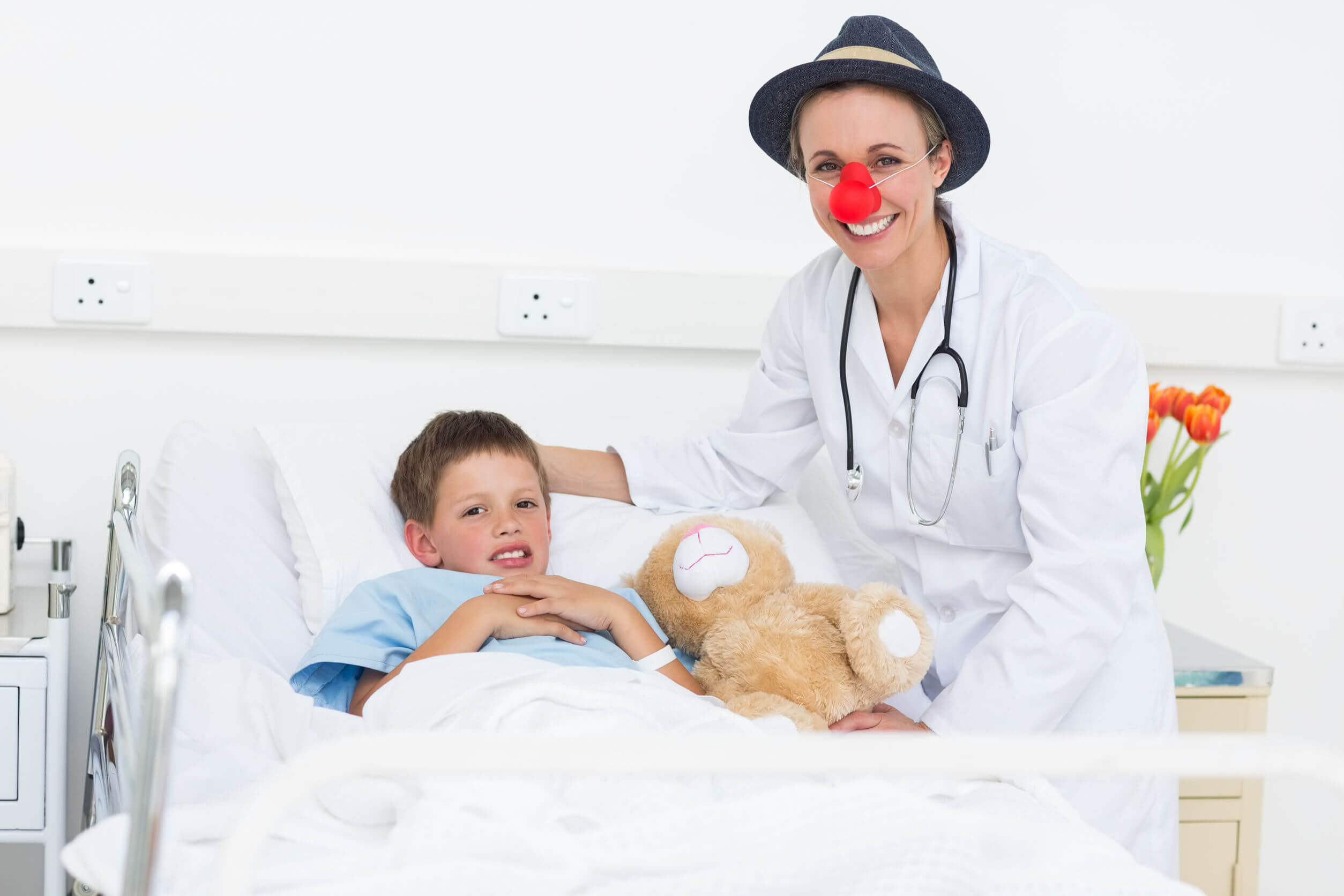 A clown doctor visiting a child in a hospital.