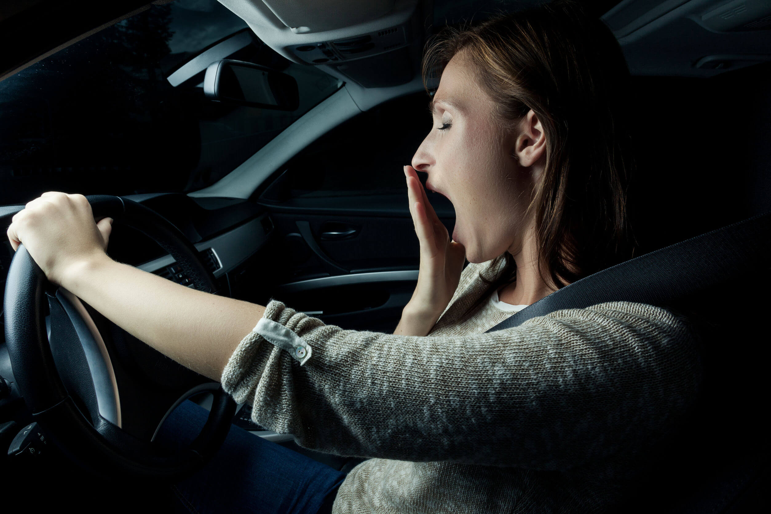 A woman yawning while driving.
