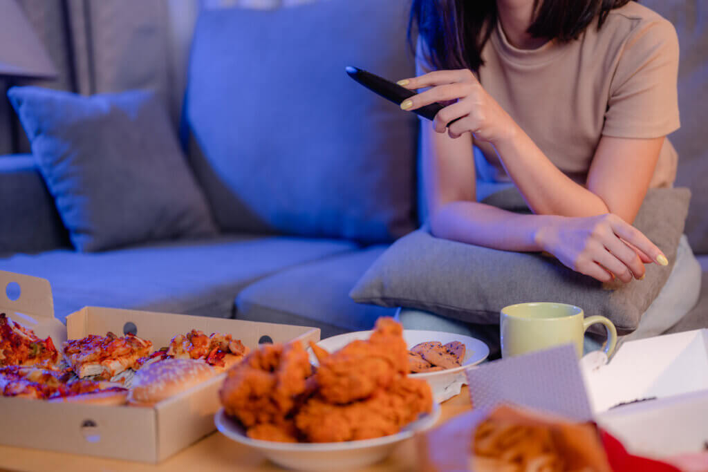 An anxious woman eating junk food and watching TV at night.