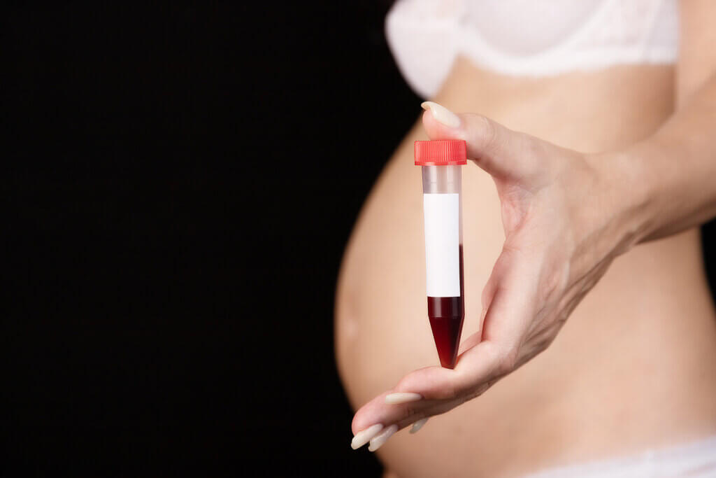 A pregnant woman holding a vial of blood.