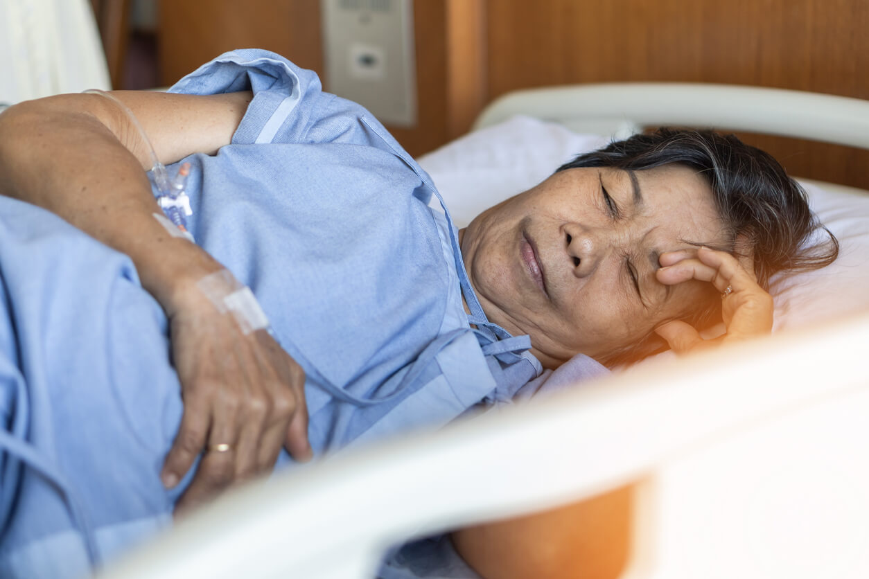Une femme âgée allongée dans un lit d'hôpital. 