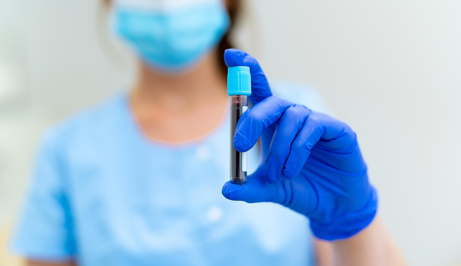  A medical professional holding a vial of blood.