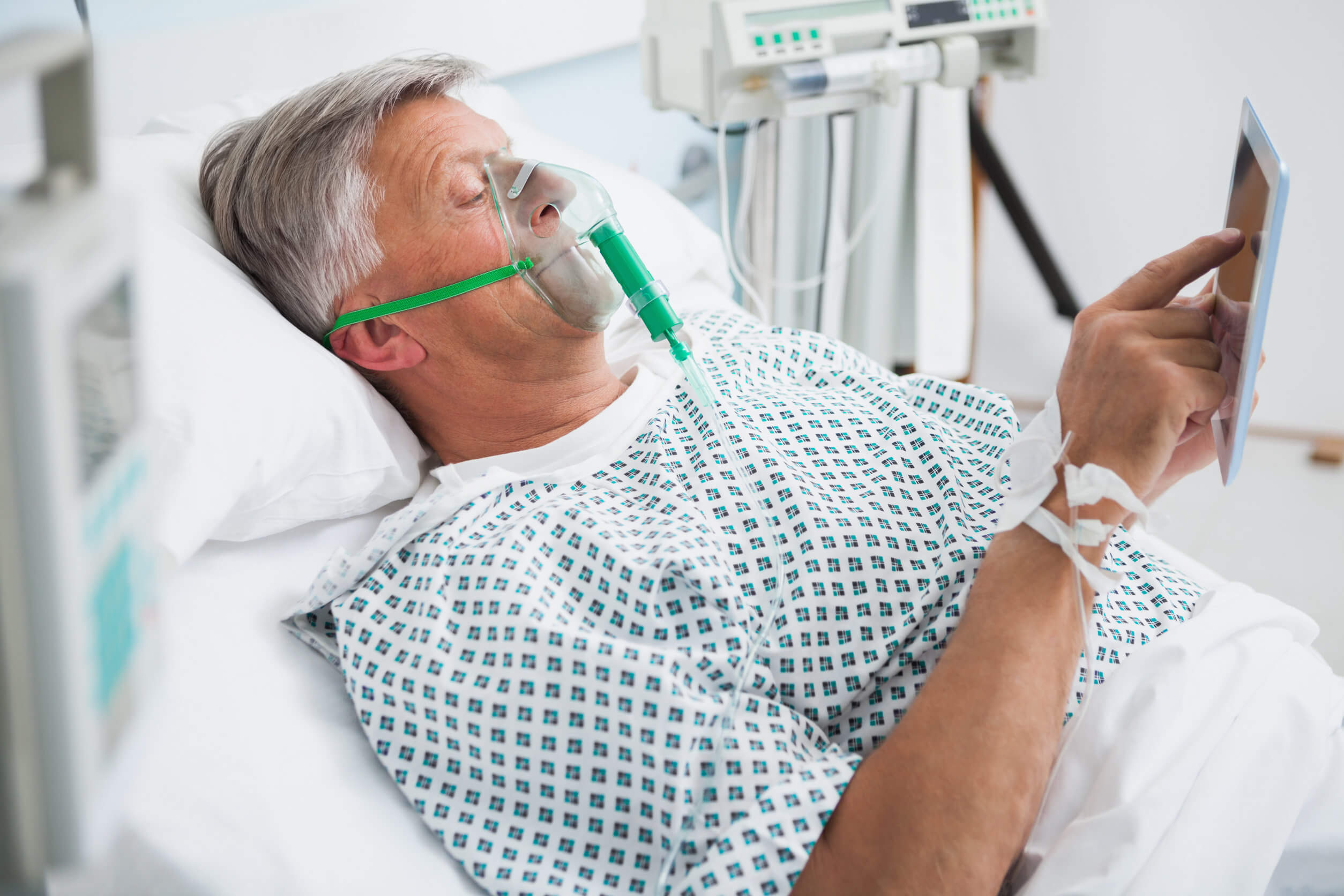 Un homme âgé sous oxygène sur un lit d'hôpital. 
