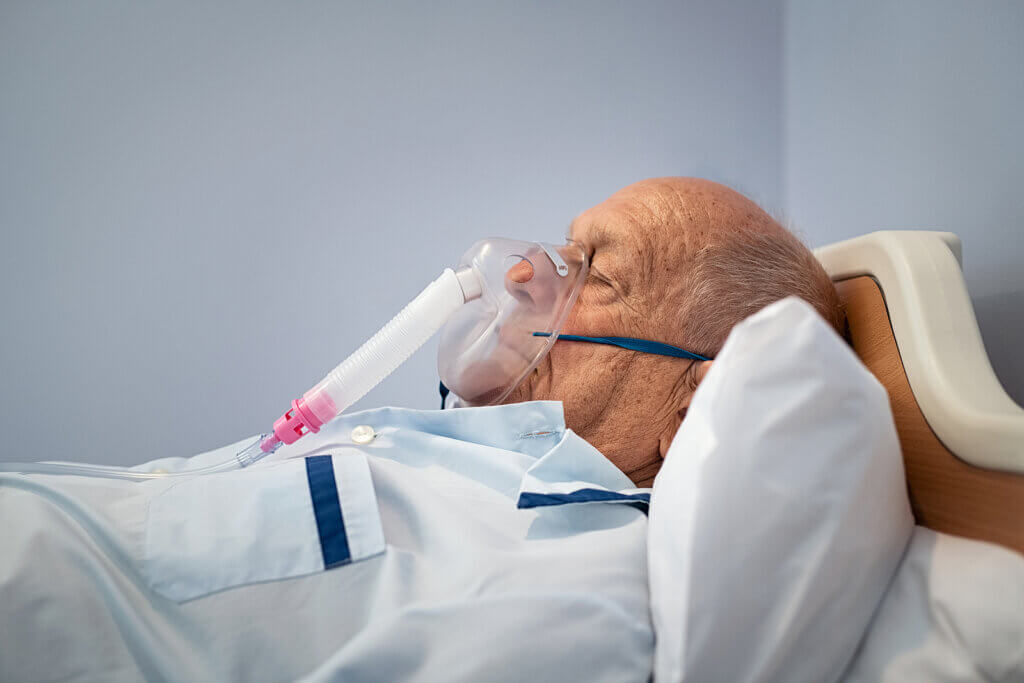 Un homme âgé allongé avec un masque à oxygène.