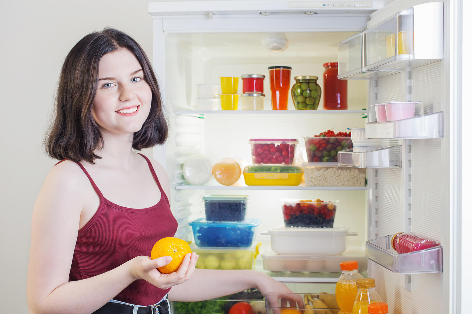 Une femme devant un réfrigérateur ouvert.