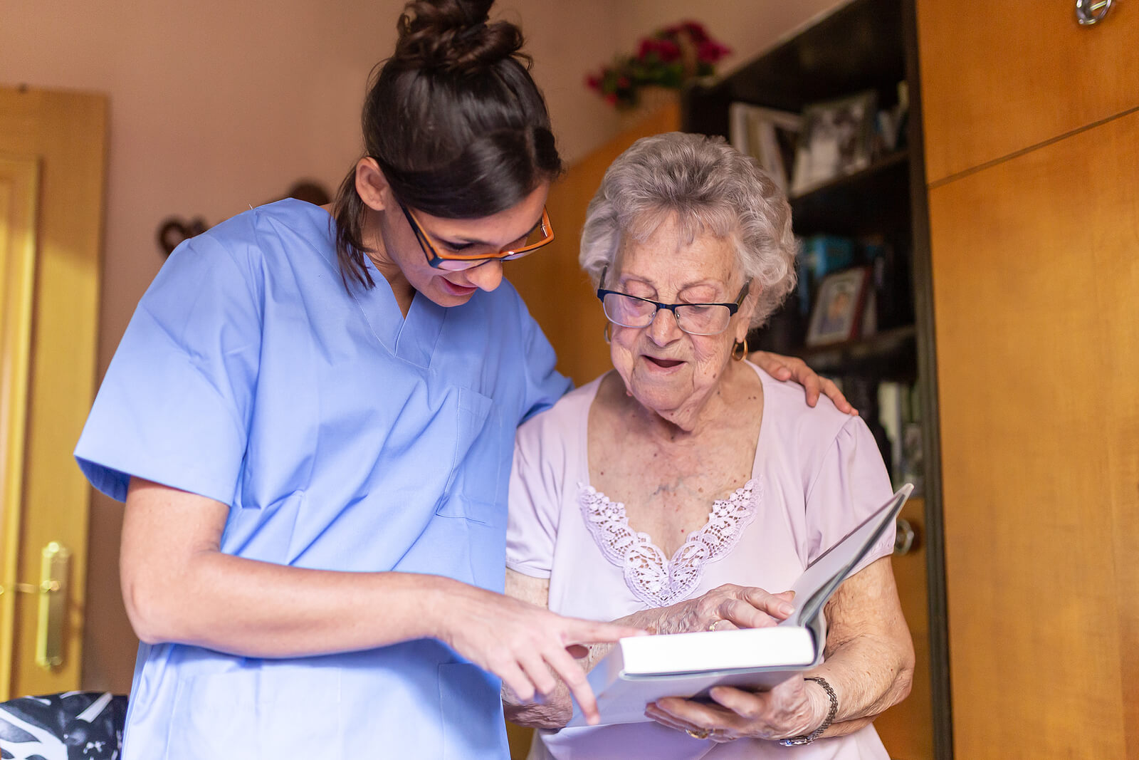 A nurse and an elderly woman looking at a book.