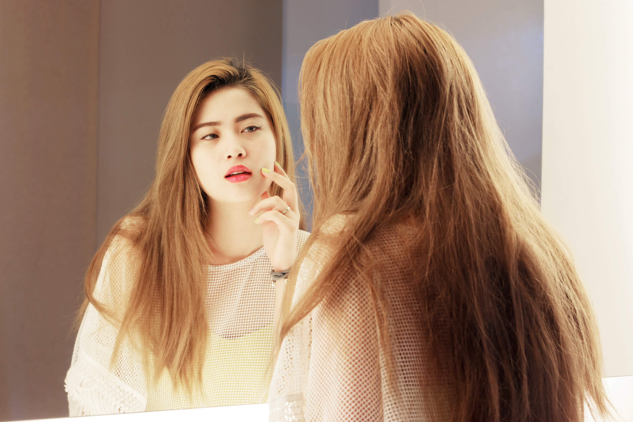 Une jeune femme qui se regarde dans le miroir. 