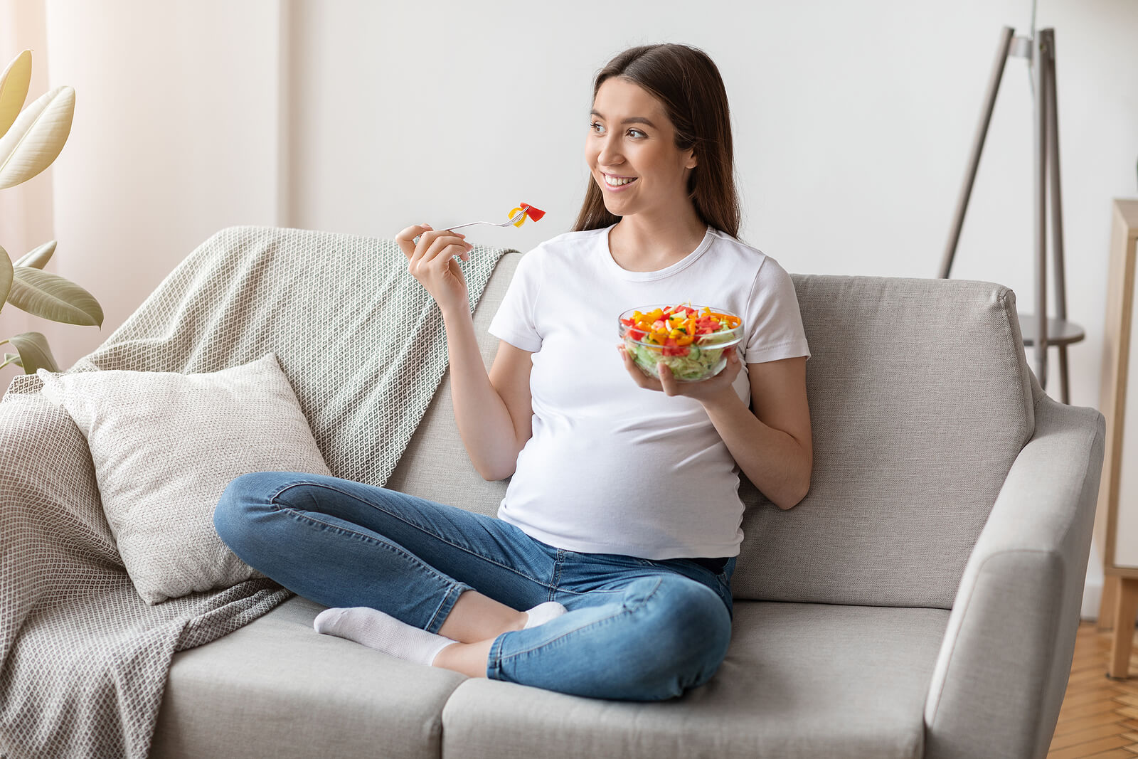 Une femme enceinte qui mange une salade. 
