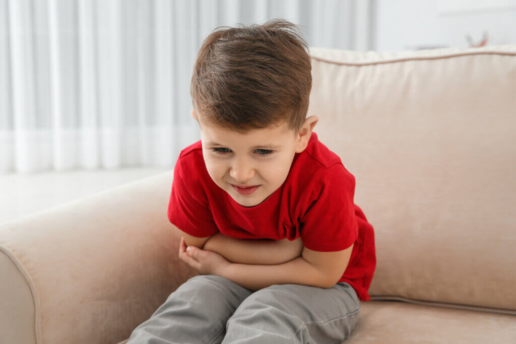 Un enfant assis qui a mal au ventre. 