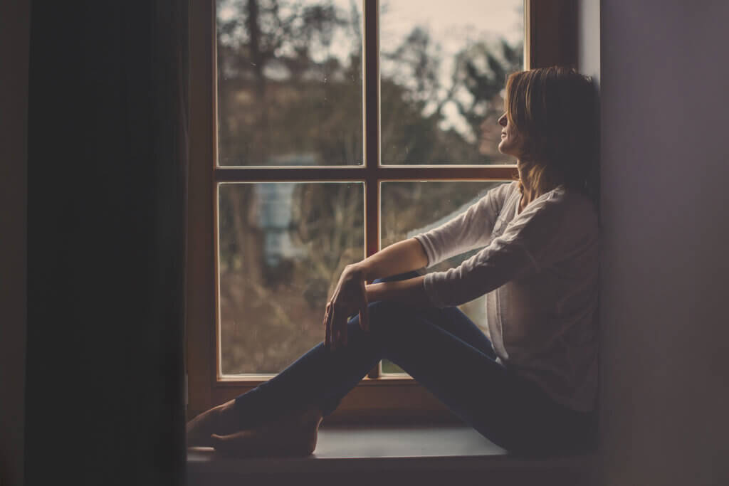Une femme assise qui regarde par la fenêtre. 