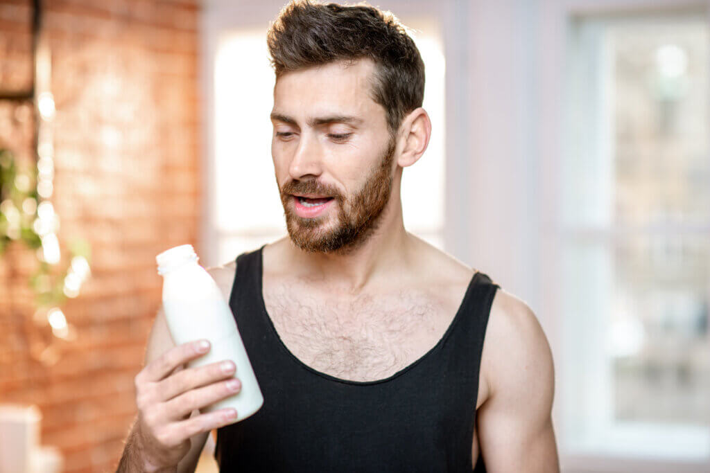 A man reading the label on a bottle of plant-based milk.