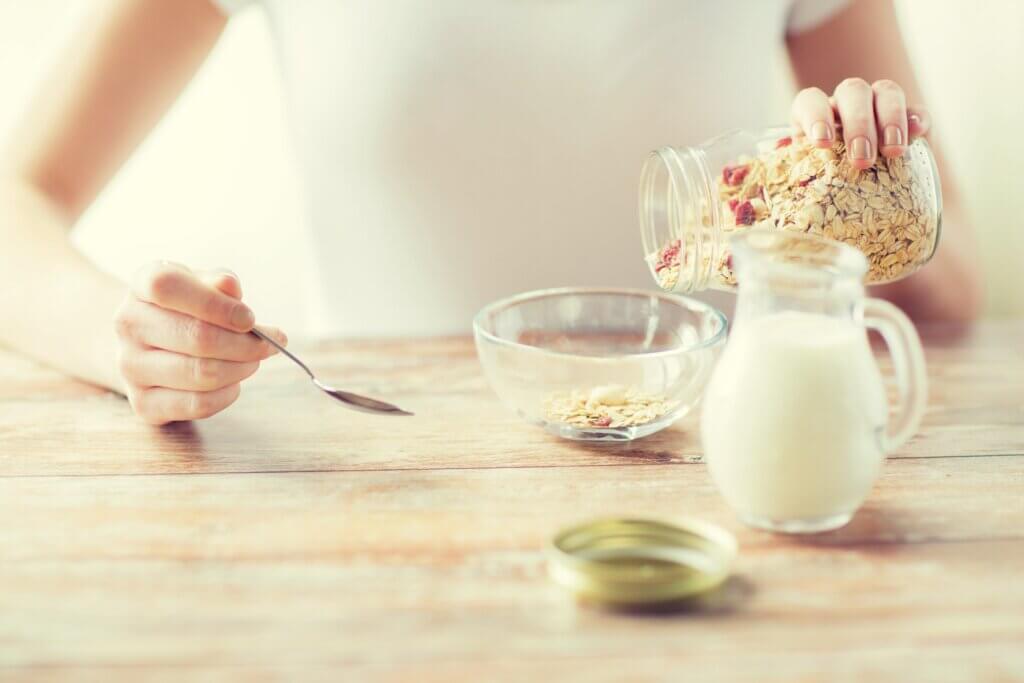 A woman pouring milk and oats into a bowl.