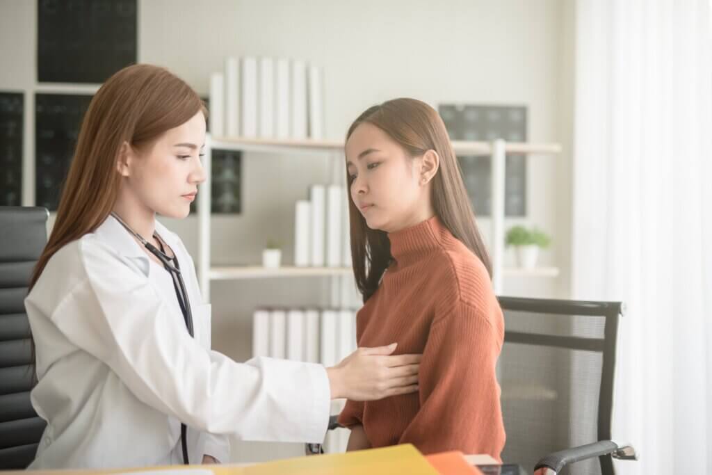 An Asian gynecologist examining an Asian patient's breast.
