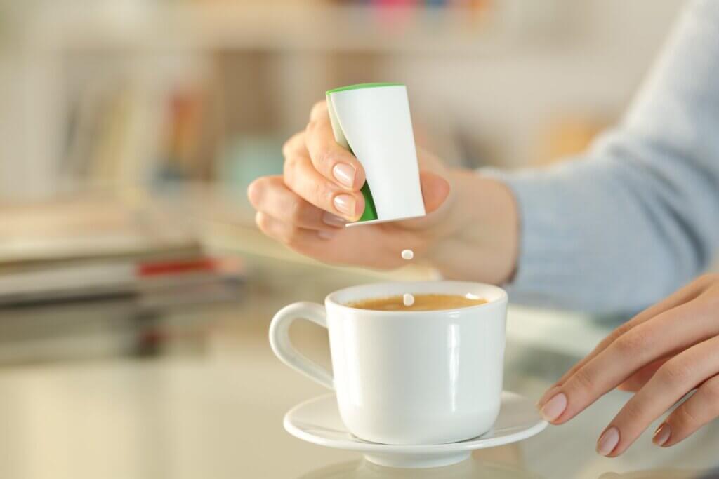 A woman adding artificial sweetener to her coffee.