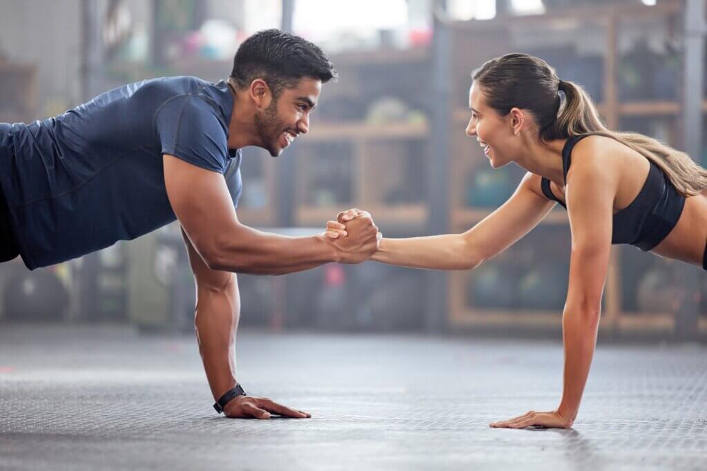A man and a woman shaking hands while exercising.